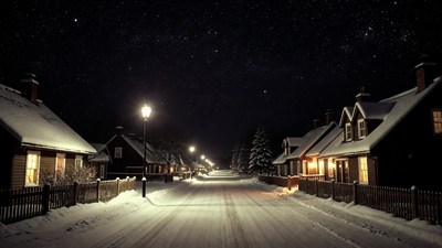 Snowy village street at night