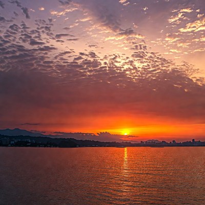 Sunset over lake with mountains and city