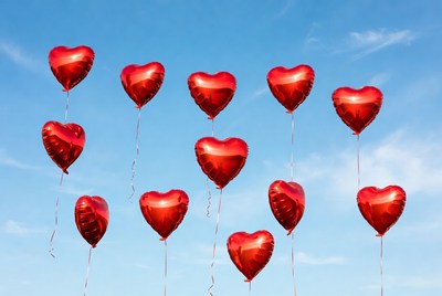 Red heart balloons floating in sky
