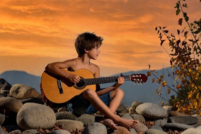Boy playing guitar at sunset