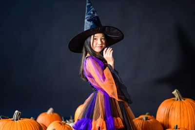 Asian girl in witch costume with pumpkins