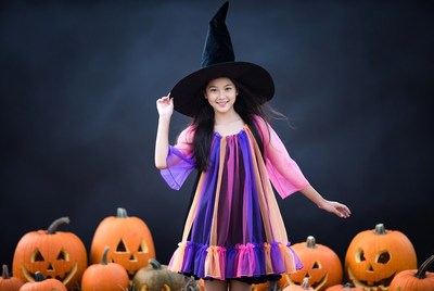 Asian girl in witch costume with pumpkins