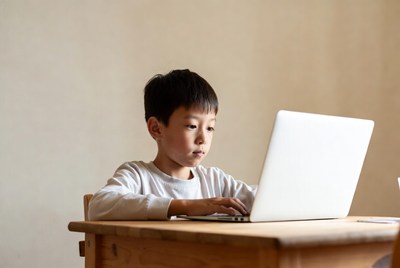 Asian boy using laptop at desk