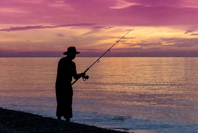 Silhouette of man fishing at sunset