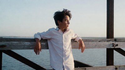 Boy leaning on pier railing over ocean