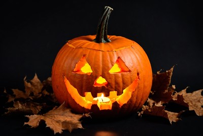 Lit Jack-o-Lantern on Autumn Leaves