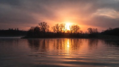 Sunset over lake with bare trees