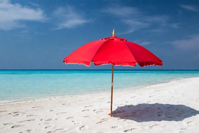 Red beach umbrella on white sand