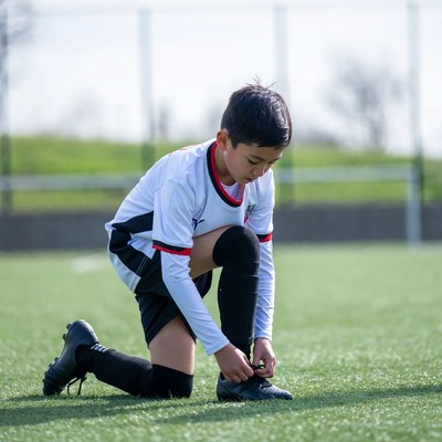 Asian boy tying soccer cleats