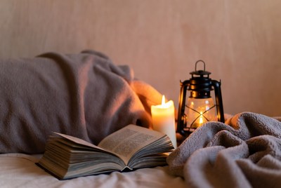 Open book by lantern on bed