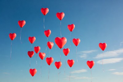 Red heart balloons floating in sky