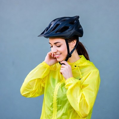 Woman adjusting bike helmet in yellow raincoat