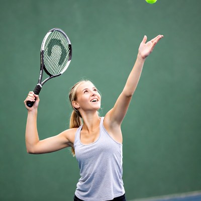 Blonde woman serving tennis ball