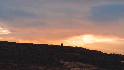 Silhouette couple on hill at sunset