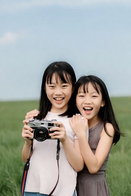 Asian girls holding camera in grass