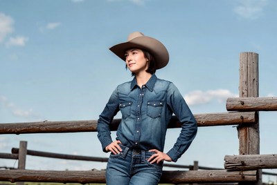 Cowgirl leaning on wooden fence