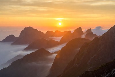 Sunset over Mountain Peaks in Clouds