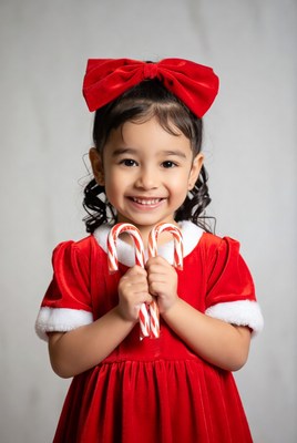 Girl holding candy canes in red Santa dress