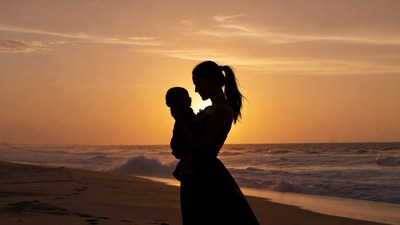 Silhouette mother holding baby at sunset beach