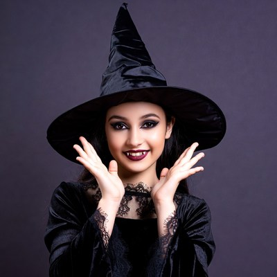 Girl in witch costume with hands raised