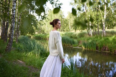 Woman in white dress by riverside trees