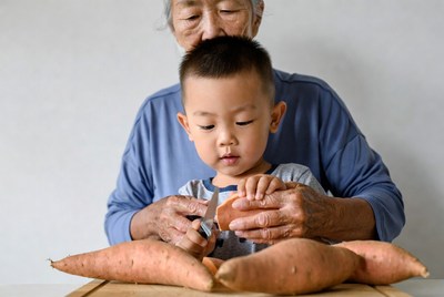 Grandmother teaching boy to cut sweet potatoes