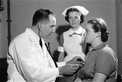 Doctor listening to patient's heart with nurse