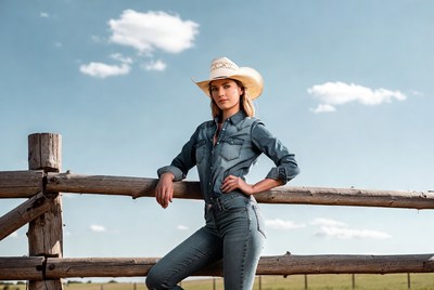 Blonde woman in cowboy hat leaning on fence