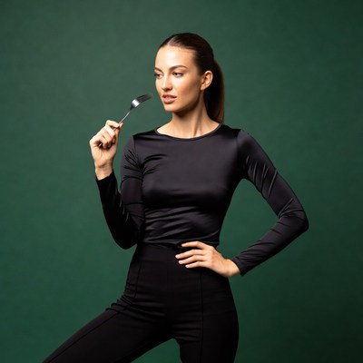 Woman holding fork on green background