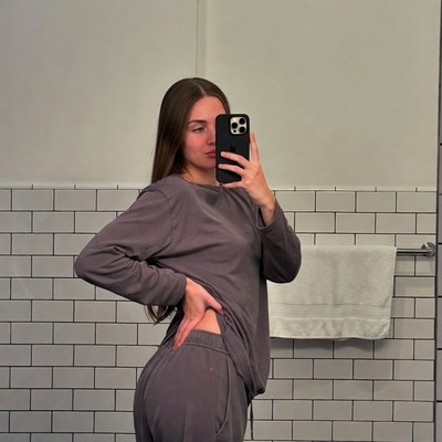 Woman taking mirror selfie in gray sweatsuit