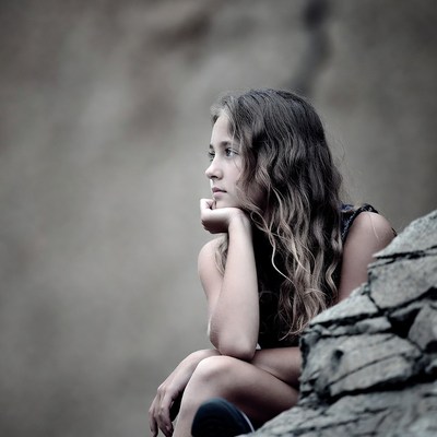 Girl sitting thoughtfully on rock