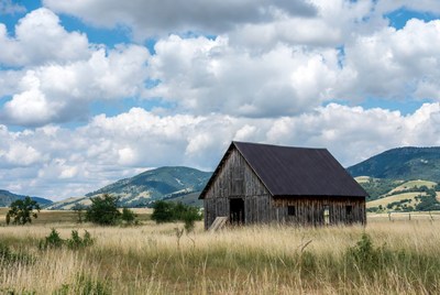 Old Barn in Grassy Field with Mountains