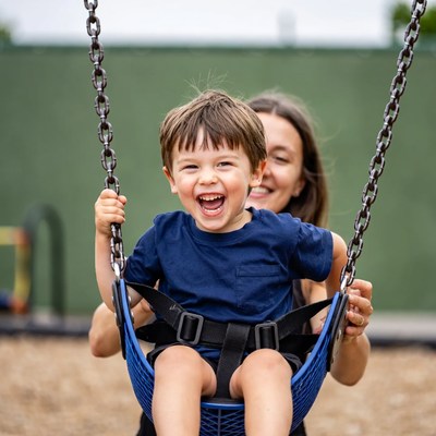 Mother pushing smiling boy on swing