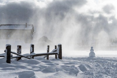 Snowman by snowy wooden fence