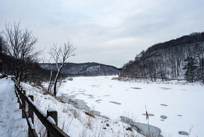 Frozen River with Snowy Hills and Path