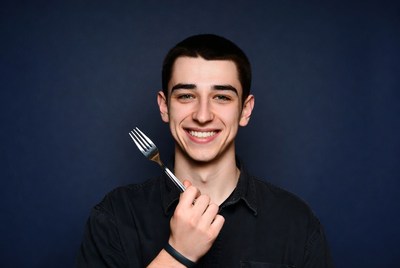 Young man holding fork smiling
