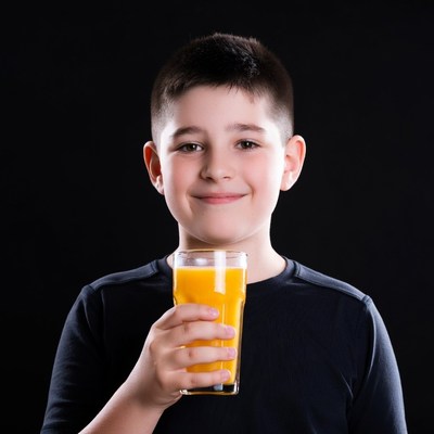 Boy holding orange juice glass