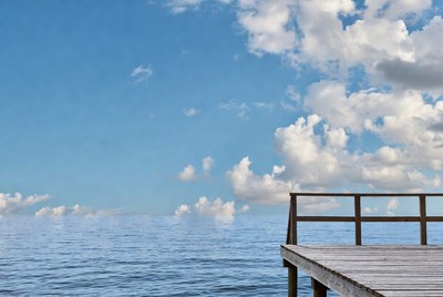 Wooden pier over ocean blue sky