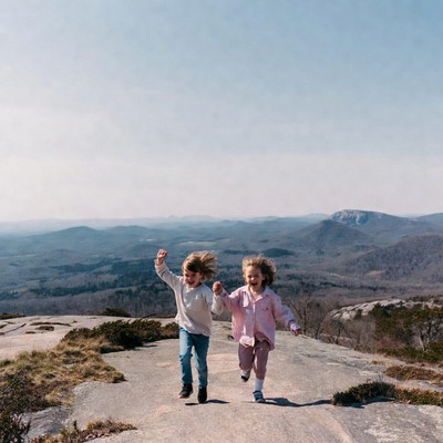 Brother and sister running on mountain overlook