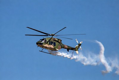 Military helicopter flying with smoke trail