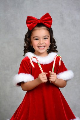 Girl in red velvet dress holding candy canes