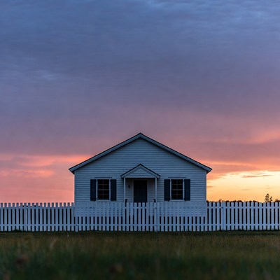 White house with picket fence at sunset