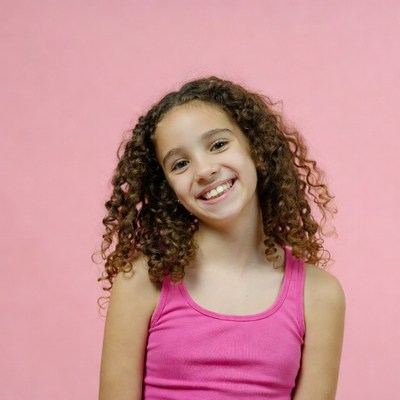 Smiling curly-haired girl in pink tank top