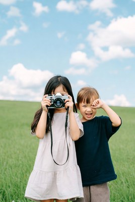 Asian girl and boy taking photo in grass
