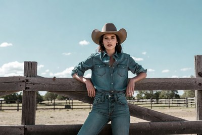 Woman in cowboy hat leaning on fence