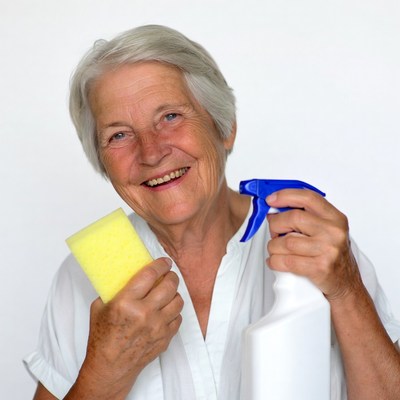 Elderly woman holding sponge and spray bottle