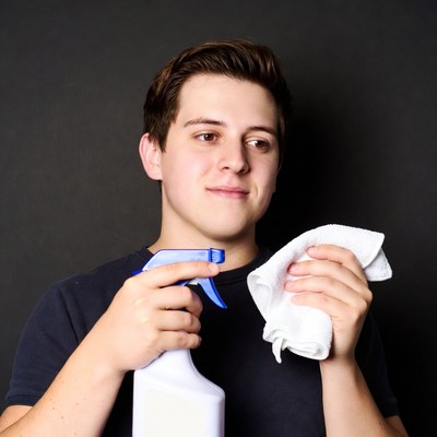 Young man holding spray bottle and cloth