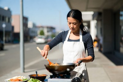 Asian woman cooking stir-fry outdoors