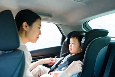 Asian mother buckling baby in car seat