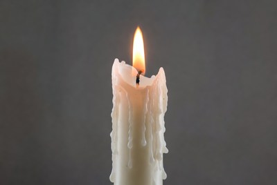Burning white candle with dripping wax